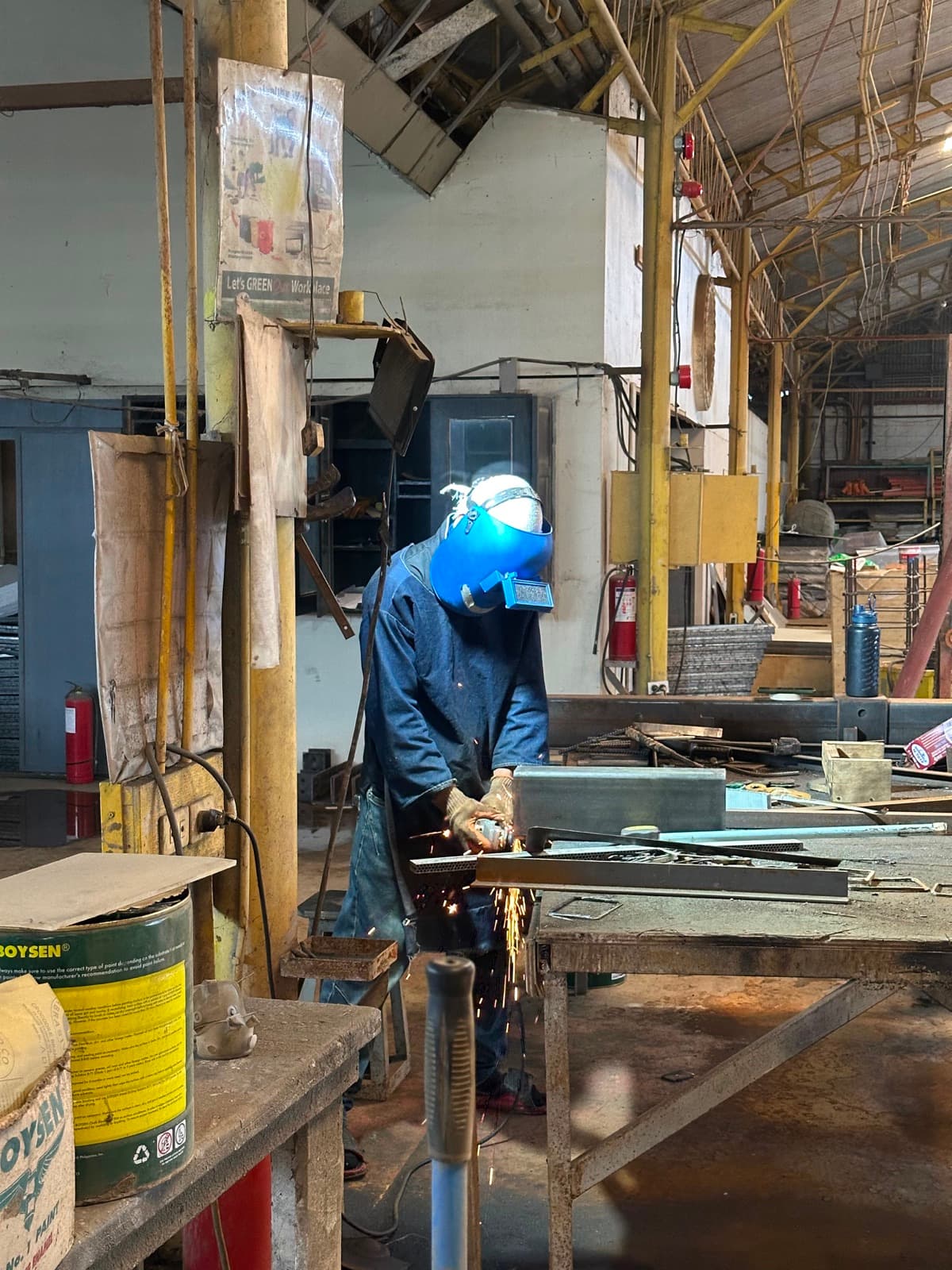 Prior plant work — fabricator grinding steel with sparks on the San Simon factory floor (not a Calma.Basic product)