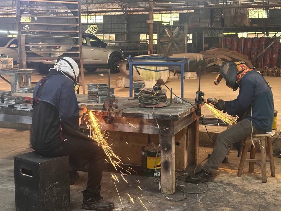 Prior plant work — metal works fabrication with grinding sparks, San Simon factory floor (not a Calma.Basic product)